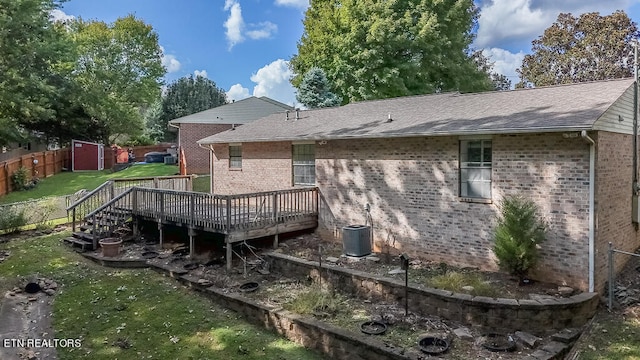 back of house featuring a wooden deck, a yard, and a storage unit