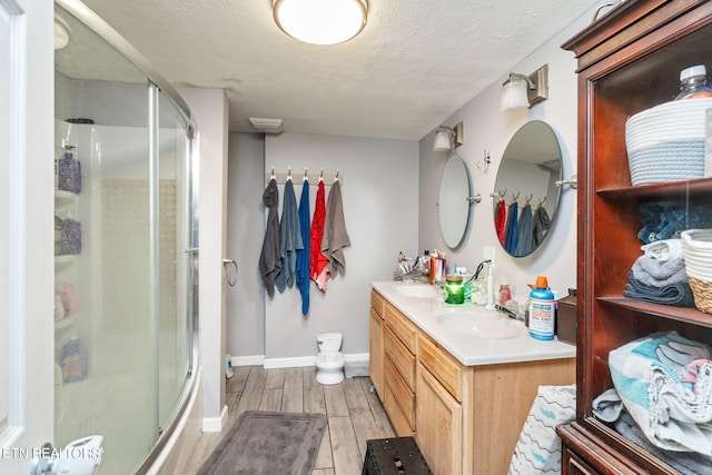 bathroom with wood-type flooring, a textured ceiling, walk in shower, and vanity