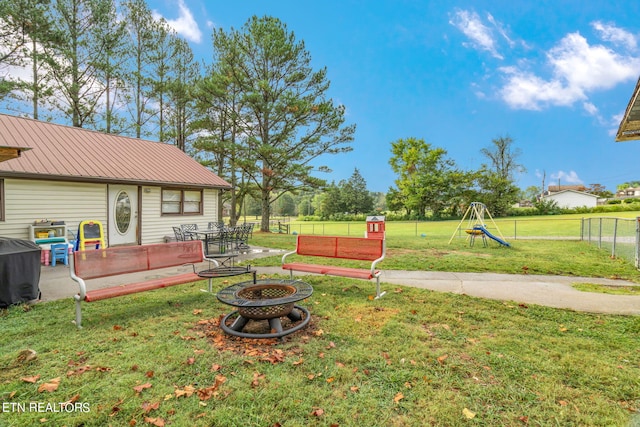 view of yard featuring a playground, a deck, and an outdoor fire pit