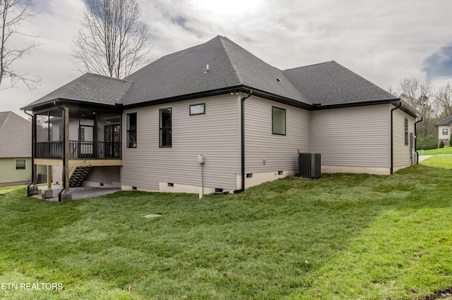 rear view of house with a lawn, central air condition unit, and a sunroom