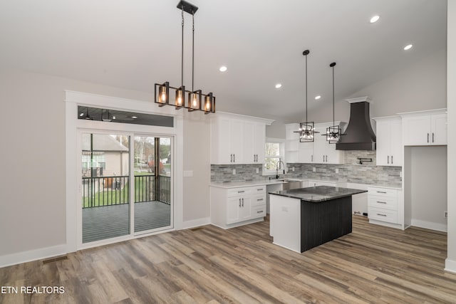 kitchen featuring premium range hood, white cabinets, a kitchen island, and wood-type flooring