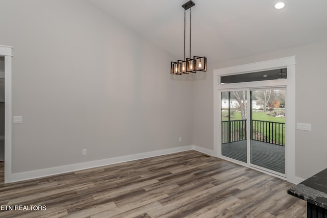 unfurnished dining area featuring hardwood / wood-style floors, vaulted ceiling, and a notable chandelier