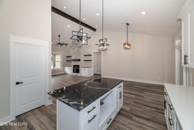 kitchen with pendant lighting, a stone fireplace, and white cabinetry