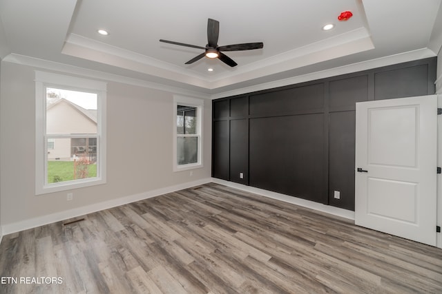 unfurnished bedroom featuring ceiling fan, light hardwood / wood-style floors, a raised ceiling, and crown molding