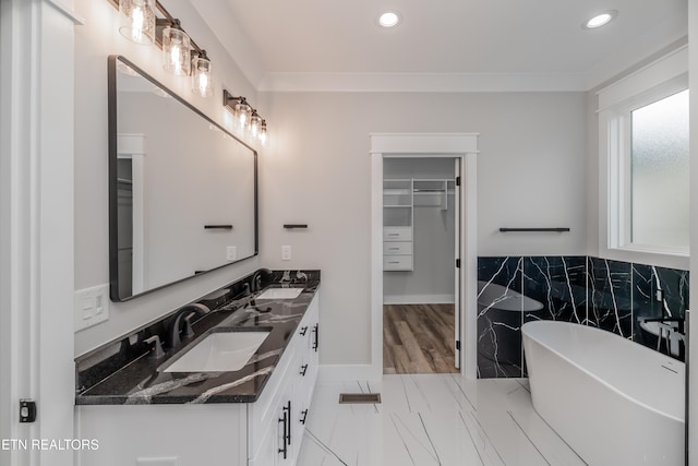 bathroom with vanity, a tub to relax in, and crown molding