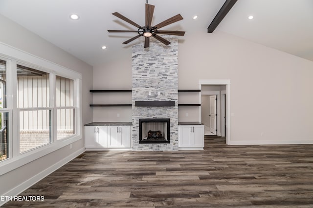 unfurnished living room with ceiling fan, beam ceiling, high vaulted ceiling, a fireplace, and dark hardwood / wood-style floors