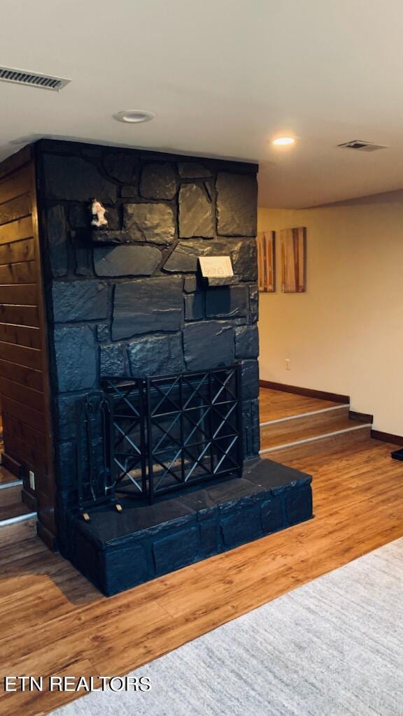 interior details featuring wood-type flooring and a stone fireplace