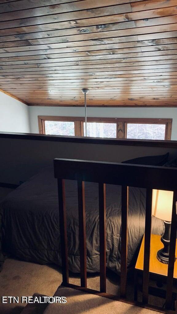 carpeted bedroom featuring wood ceiling and multiple windows