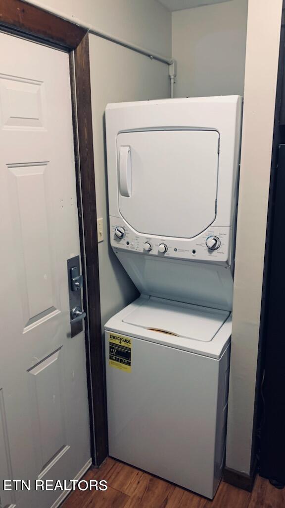 washroom with stacked washing maching and dryer and dark wood-type flooring