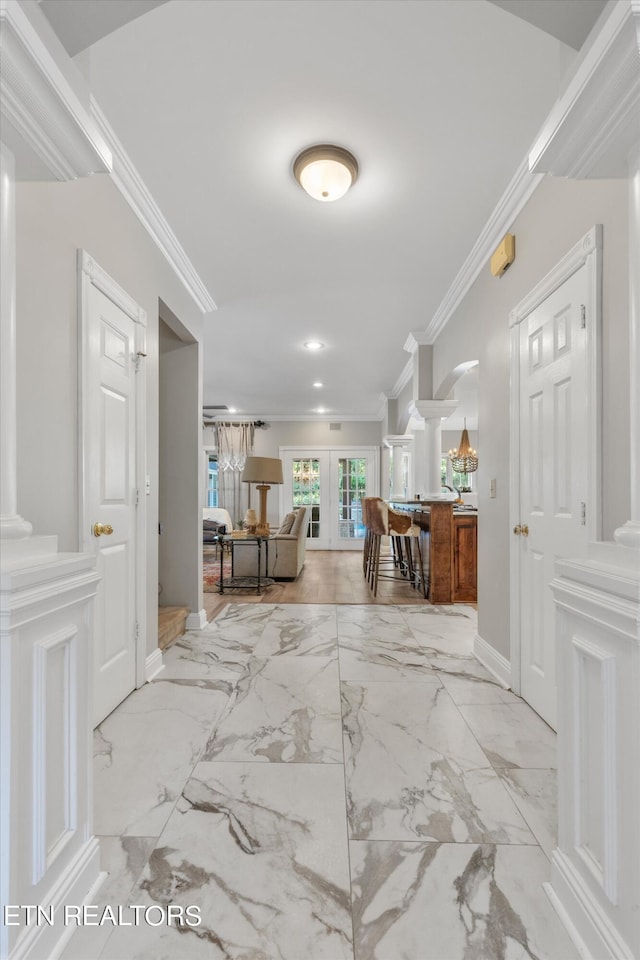 corridor with ornamental molding, french doors, and ornate columns