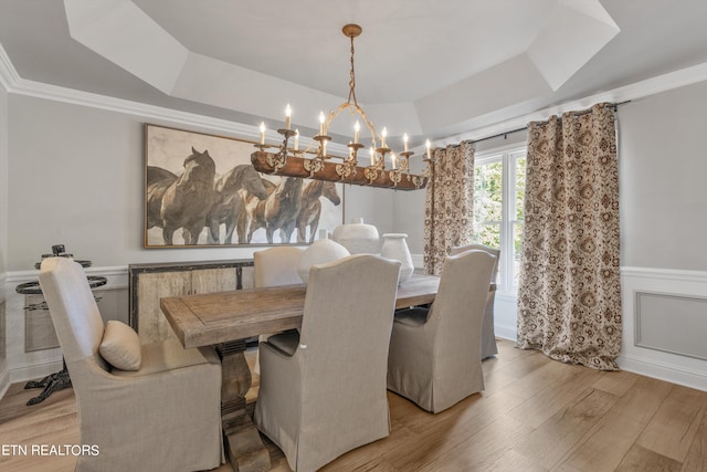 dining space with an inviting chandelier, light hardwood / wood-style flooring, crown molding, and a tray ceiling