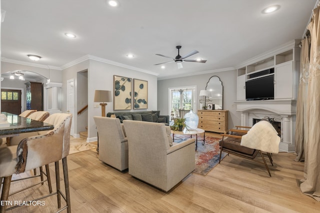 living room with ceiling fan, crown molding, and light hardwood / wood-style floors