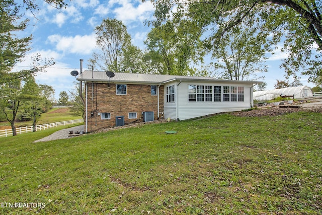 rear view of house with a lawn and cooling unit