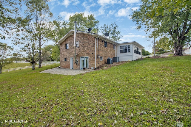 back of property featuring a lawn, cooling unit, and a patio area