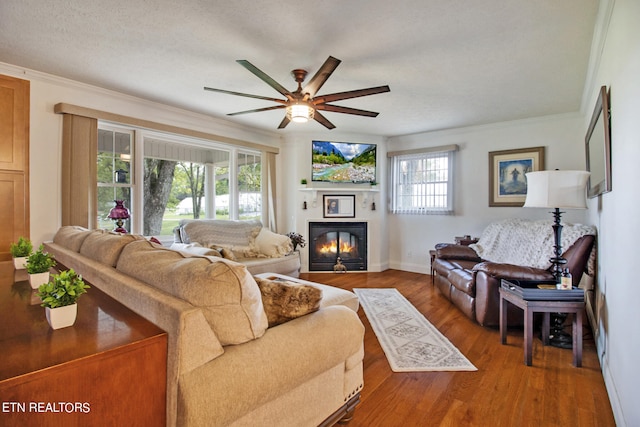 living room featuring a textured ceiling, hardwood / wood-style flooring, ceiling fan, and crown molding