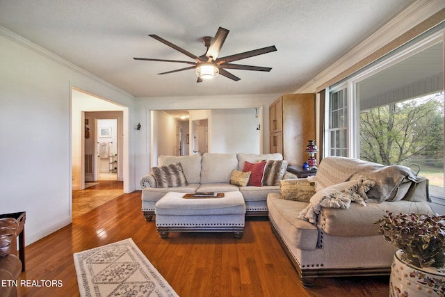 living room with crown molding, ceiling fan, and dark wood-type flooring