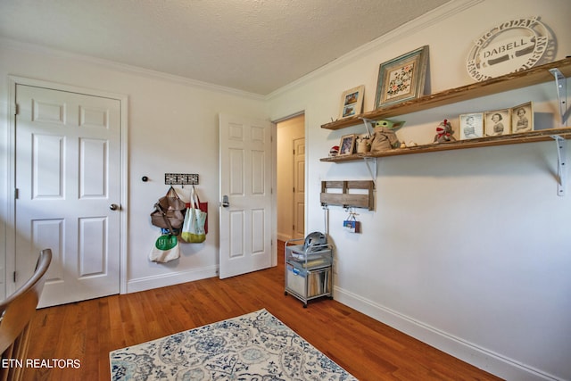 interior space with a textured ceiling, crown molding, and hardwood / wood-style flooring