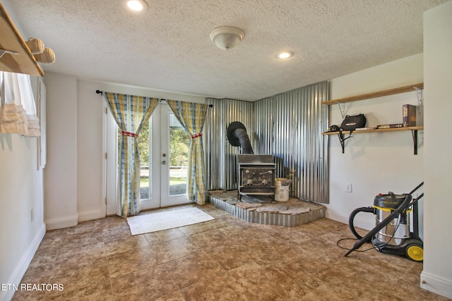 interior space featuring french doors, a textured ceiling, and a wood stove