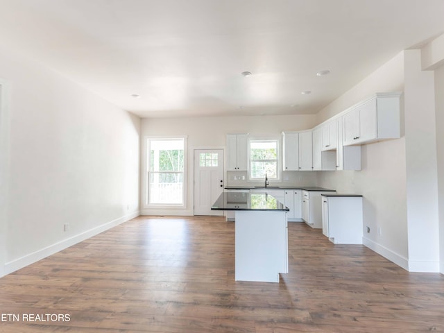 kitchen with sink, a kitchen island, hardwood / wood-style floors, and white cabinetry