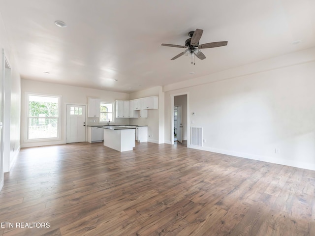 unfurnished living room featuring wood-type flooring, sink, and ceiling fan