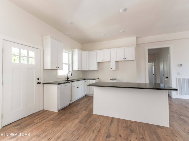 kitchen featuring wood-type flooring, white dishwasher, sink, and white cabinetry