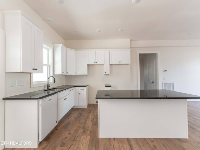 kitchen with white dishwasher, a kitchen island, and white cabinetry