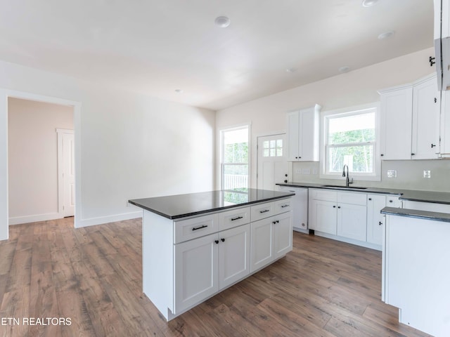 kitchen featuring white dishwasher, wood-type flooring, white cabinetry, and plenty of natural light