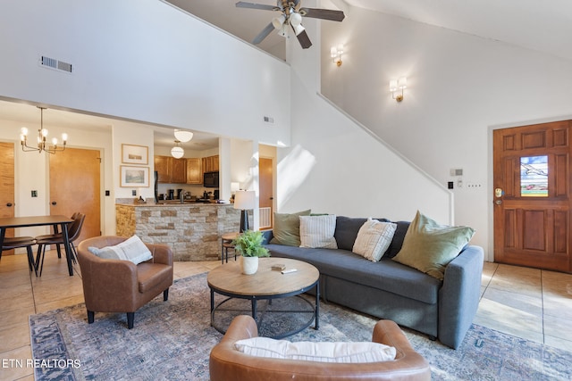 tiled living room with high vaulted ceiling and ceiling fan with notable chandelier