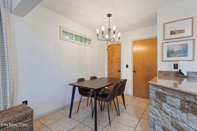 dining space featuring light tile patterned flooring, a textured ceiling, and an inviting chandelier