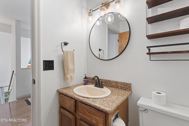 bathroom featuring vanity, a textured ceiling, wood-type flooring, and toilet