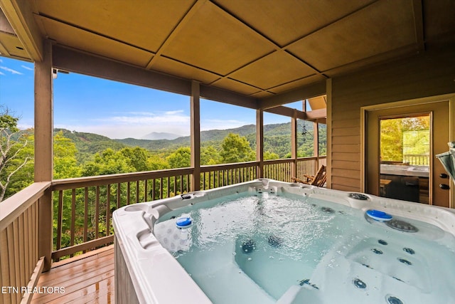 view of pool with a deck with mountain view and a hot tub