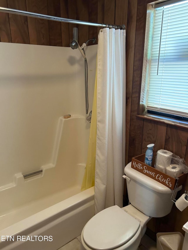 bathroom with tile patterned flooring, toilet, shower / bathtub combination with curtain, and wooden walls