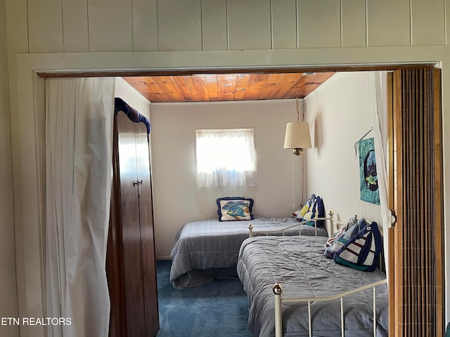 bedroom featuring wood ceiling and dark carpet