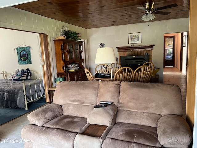 tiled living room featuring ceiling fan, wood ceiling, and a brick fireplace