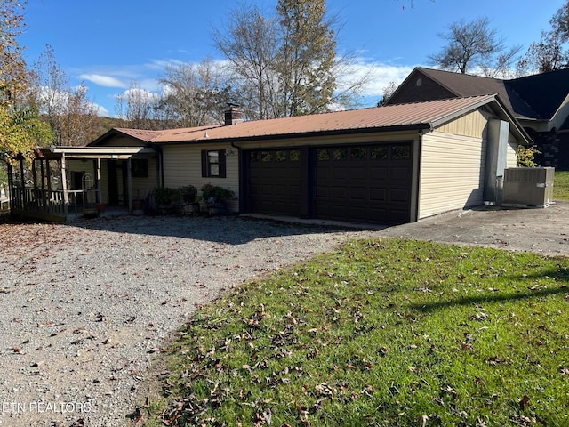 view of front of house featuring covered porch, cooling unit, a garage, and a front lawn