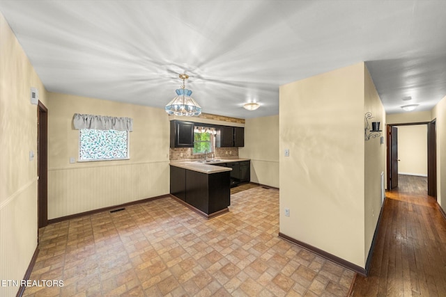 kitchen with light hardwood / wood-style floors, sink, a notable chandelier, decorative backsplash, and decorative light fixtures