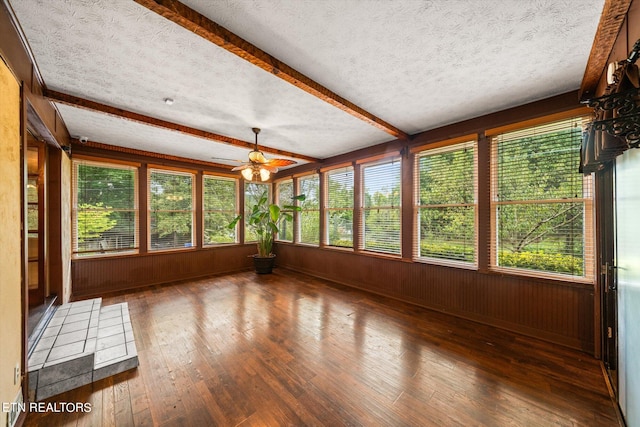 unfurnished sunroom with ceiling fan, beamed ceiling, and a healthy amount of sunlight