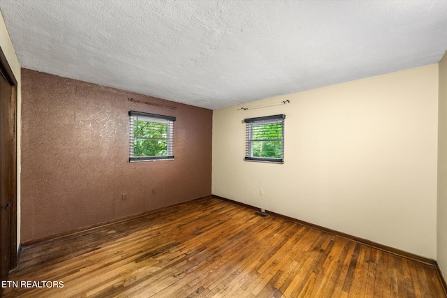 unfurnished room with a textured ceiling and wood-type flooring