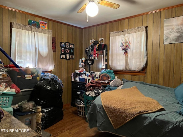 bedroom with ceiling fan, hardwood / wood-style flooring, ornamental molding, and wood walls