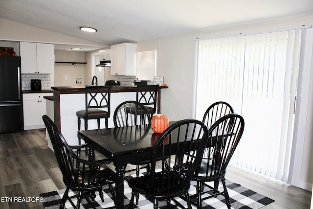 dining area with vaulted ceiling, sink, and dark hardwood / wood-style flooring