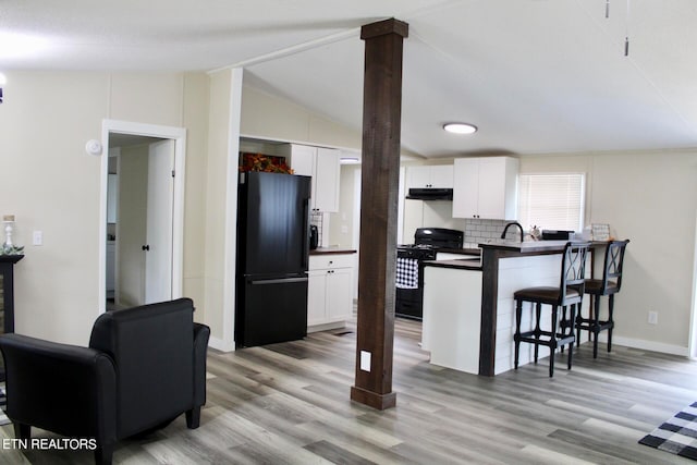 kitchen featuring white cabinets, light wood-type flooring, vaulted ceiling, and black appliances