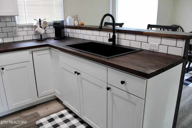 kitchen featuring decorative backsplash, white cabinets, sink, and butcher block counters