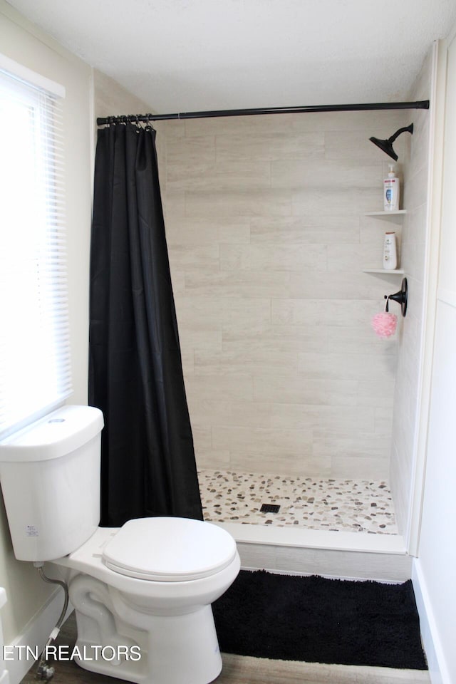 bathroom with a shower with shower curtain and toilet