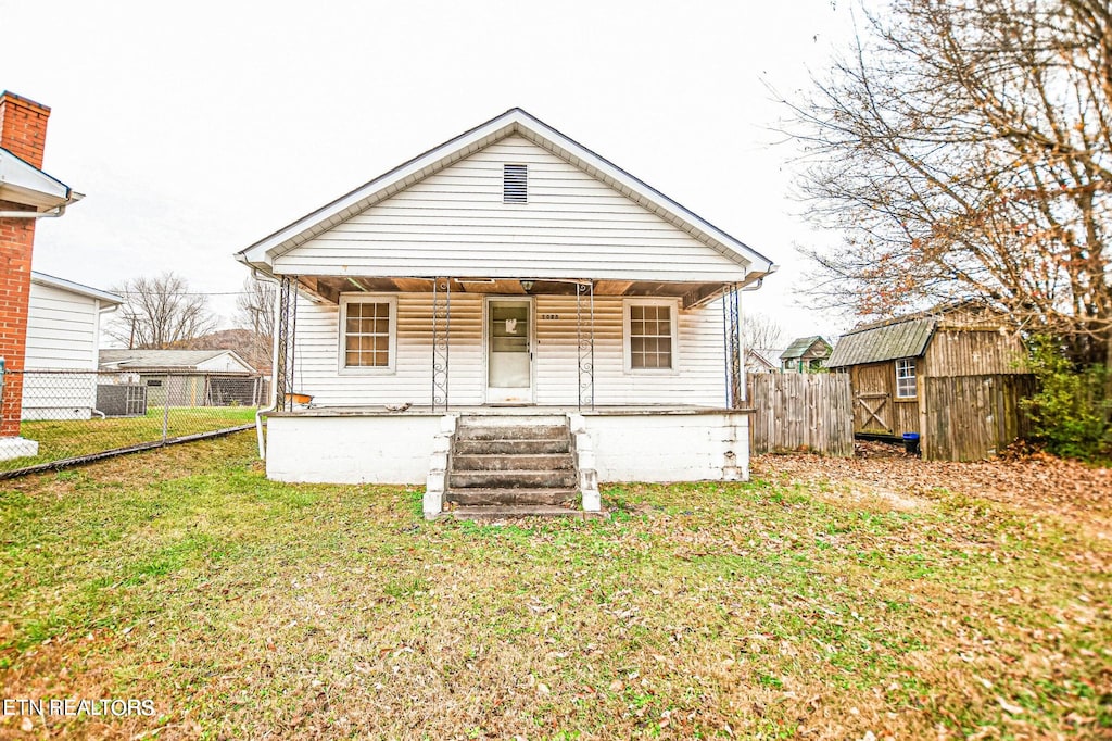 back of house with a lawn and a storage unit