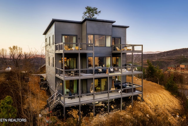 back house at dusk featuring a balcony