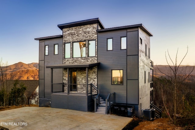 back house at dusk featuring a mountain view and central AC unit