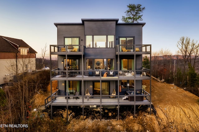 back house at dusk with a balcony