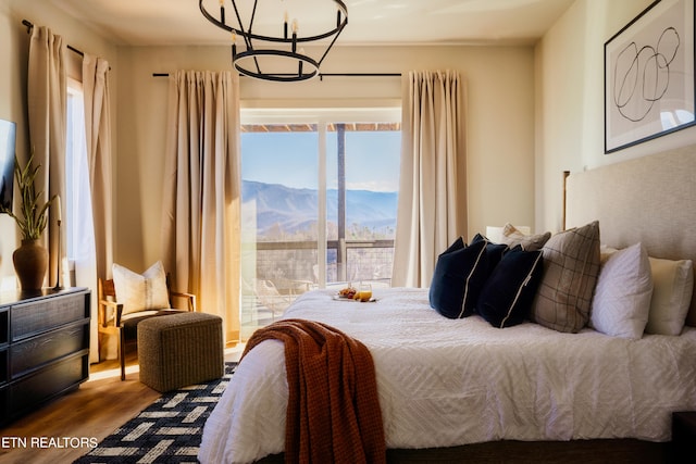 bedroom with a mountain view, hardwood / wood-style flooring, and a chandelier