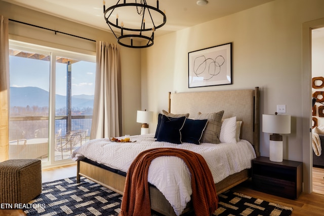 bedroom with hardwood / wood-style floors, a chandelier, and a mountain view