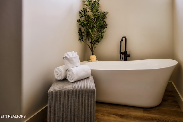 interior space with a tub to relax in and wood-type flooring